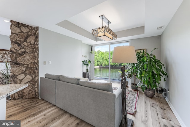 living area with wood finished floors and a tray ceiling