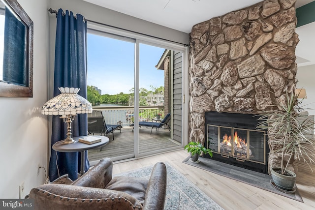 living area with wood finished floors and a stone fireplace