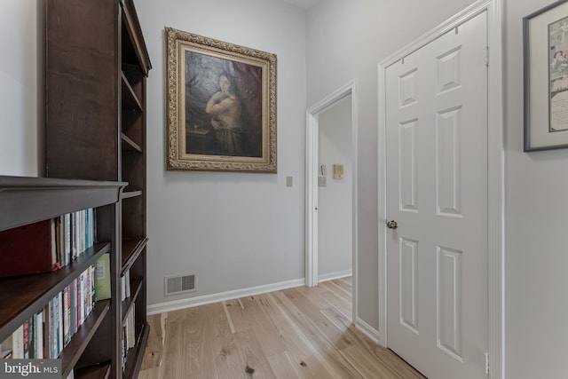 corridor featuring light wood-style floors and baseboards