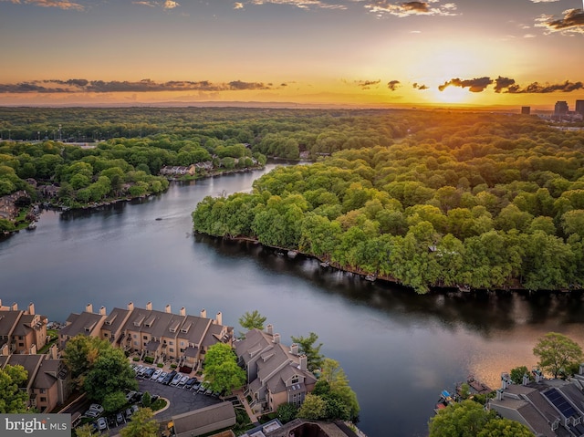 aerial view at dusk of a water view, a view of trees, and a residential view