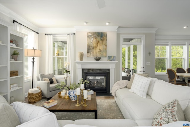 living room featuring crown molding, plenty of natural light, and a glass covered fireplace