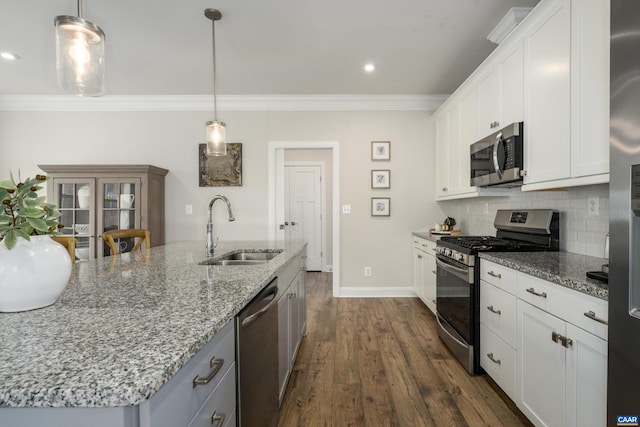 kitchen with ornamental molding, light stone countertops, white cabinets, a sink, and appliances with stainless steel finishes