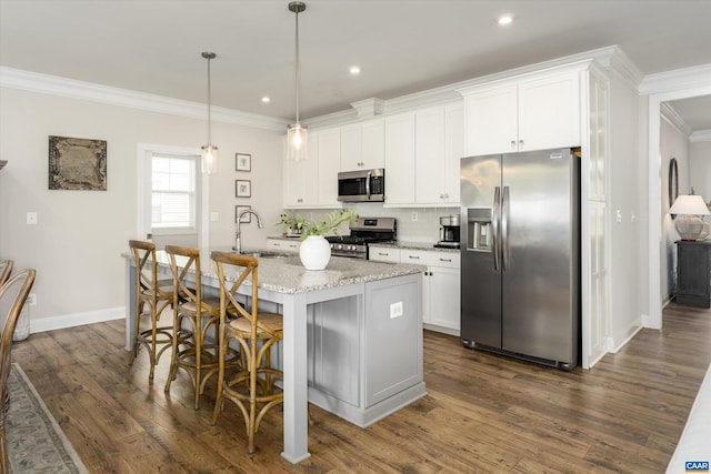 kitchen with ornamental molding, a kitchen island with sink, a kitchen bar, dark wood finished floors, and appliances with stainless steel finishes