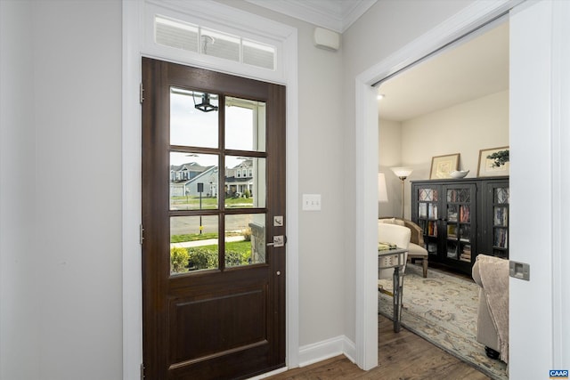 foyer entrance featuring crown molding, baseboards, and wood finished floors