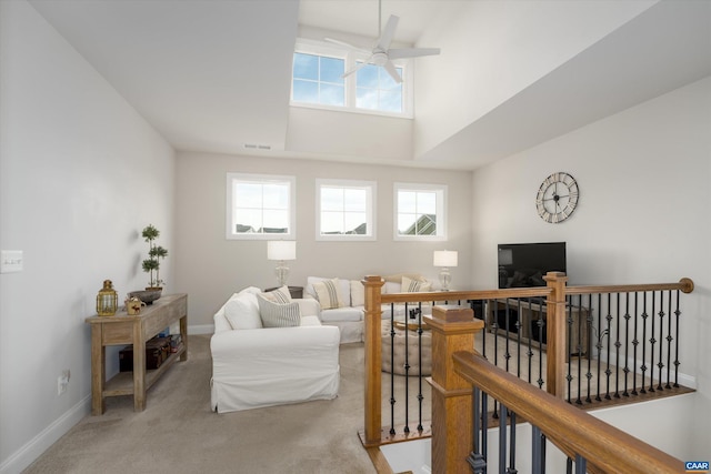 carpeted living area with visible vents, a ceiling fan, baseboards, and plenty of natural light