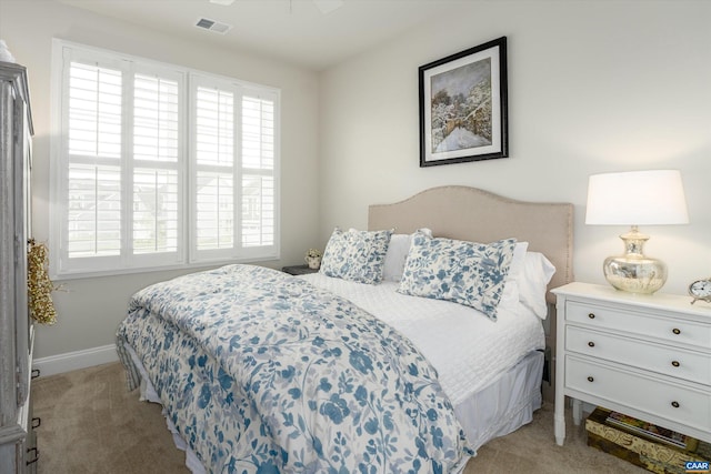bedroom with baseboards, visible vents, and light colored carpet
