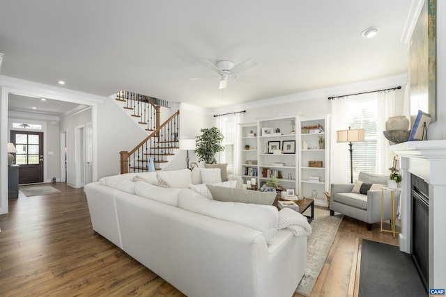 living area with a ceiling fan, a glass covered fireplace, wood finished floors, and stairway