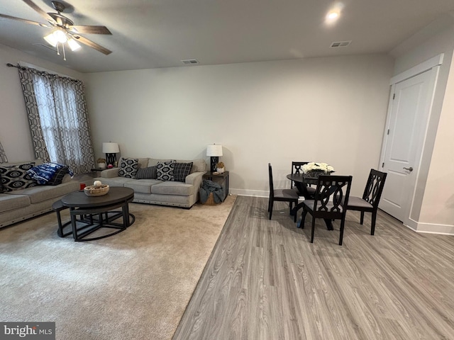living room with wood finished floors, ceiling fan, visible vents, and baseboards