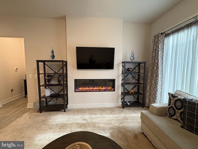 carpeted living room featuring baseboards and a glass covered fireplace