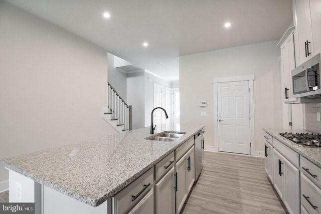 kitchen featuring a sink, stainless steel appliances, recessed lighting, light wood finished floors, and an island with sink