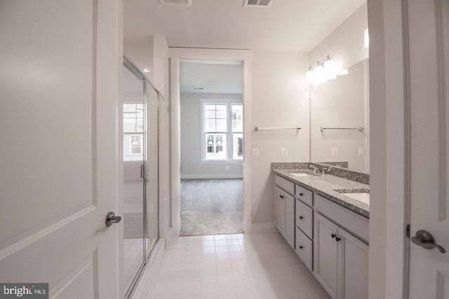 bathroom with a shower stall, tile patterned flooring, double vanity, and a sink