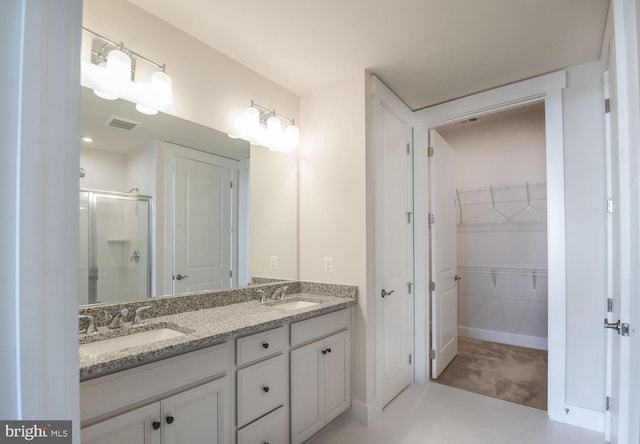 bathroom featuring a walk in closet, visible vents, a stall shower, and a sink
