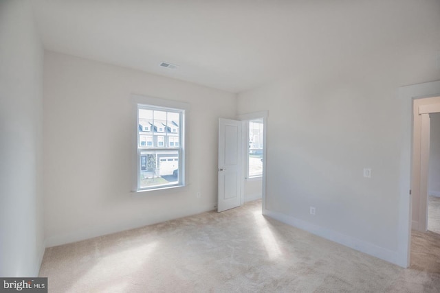 carpeted empty room featuring visible vents and a healthy amount of sunlight