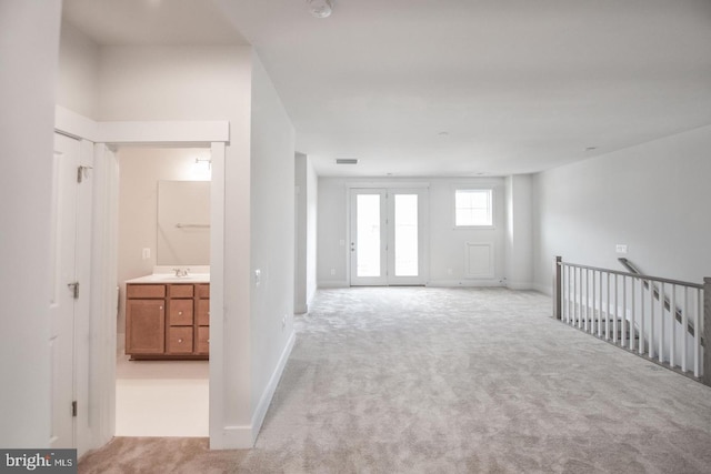 interior space featuring a sink, baseboards, light carpet, and visible vents