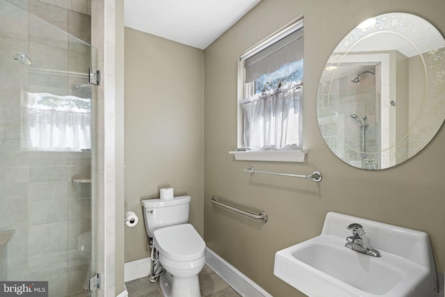 bathroom with toilet, baseboards, tile patterned floors, a shower stall, and a sink