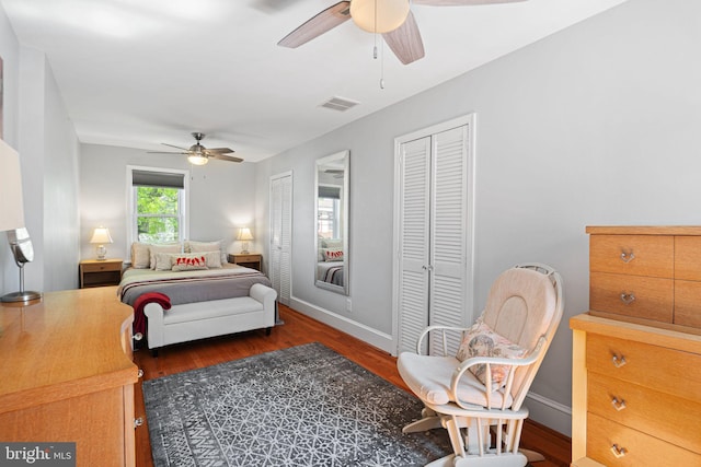 bedroom featuring multiple closets, baseboards, wood finished floors, and visible vents