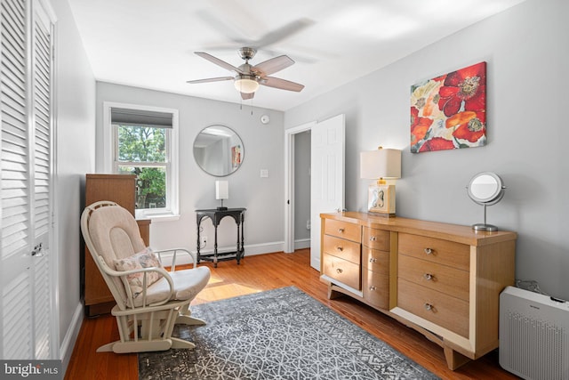 living area with baseboards, ceiling fan, and wood finished floors