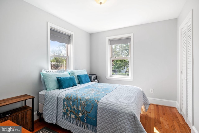 bedroom with baseboards, multiple windows, and wood finished floors