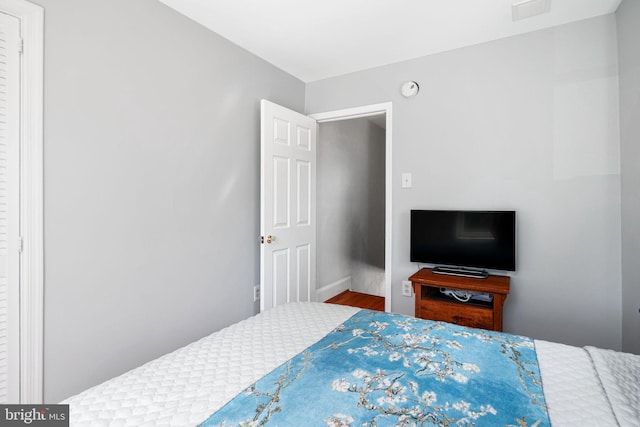 bedroom with visible vents, baseboards, and wood finished floors