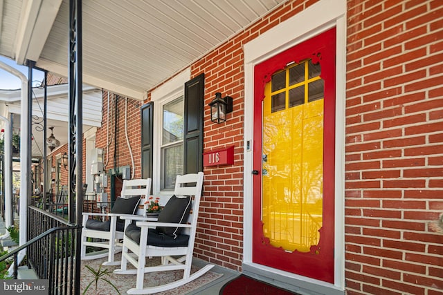 property entrance with brick siding and a porch