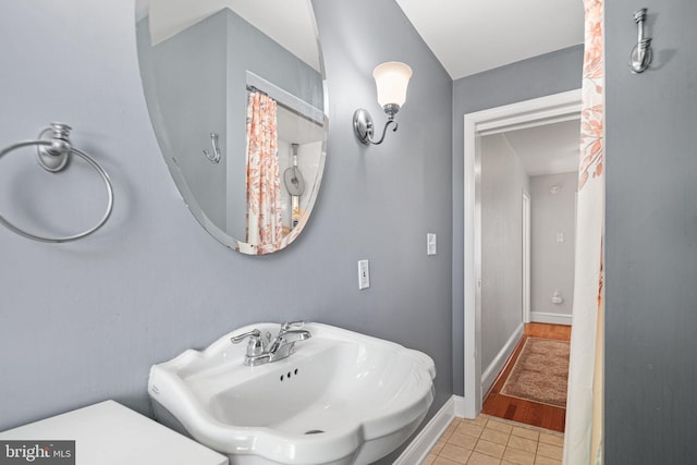 bathroom with tile patterned flooring, a sink, and baseboards