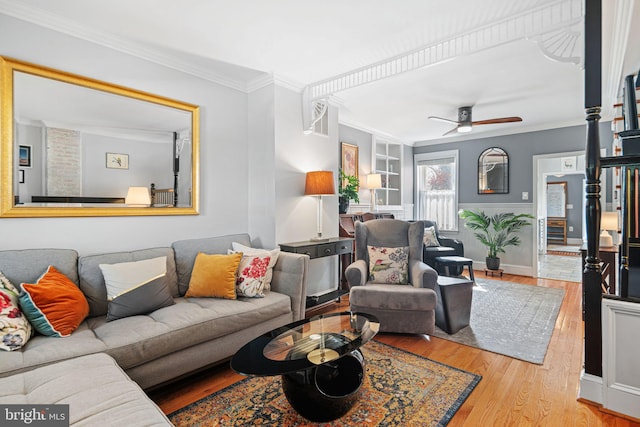 living room featuring crown molding, baseboards, ceiling fan, and wood finished floors