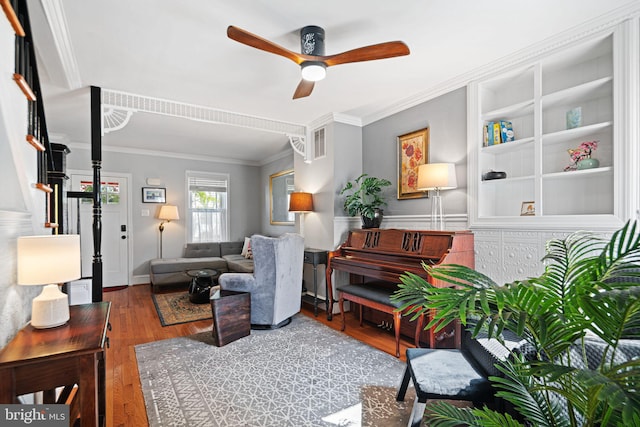 living room with crown molding, ceiling fan, stairway, and wood finished floors