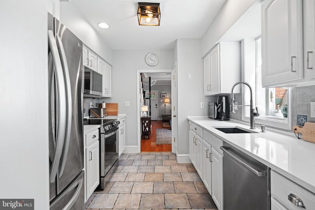 kitchen with light countertops, white cabinets, tasteful backsplash, a sink, and appliances with stainless steel finishes