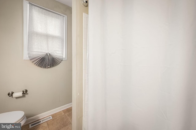 bathroom featuring baseboards, visible vents, tile patterned floors, and toilet