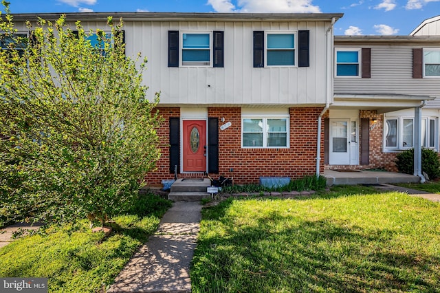 multi unit property featuring a front lawn and brick siding