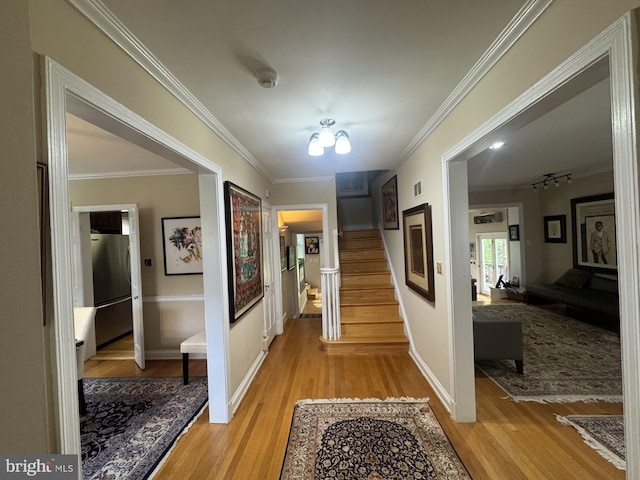 hall with light wood finished floors, stairway, crown molding, visible vents, and baseboards