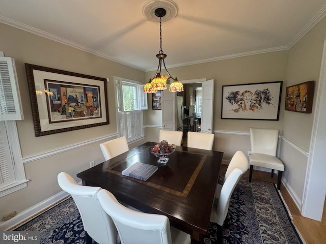 dining space with ornamental molding, wood finished floors, and baseboards