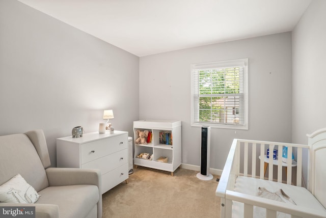 bedroom featuring a crib, baseboards, and light carpet