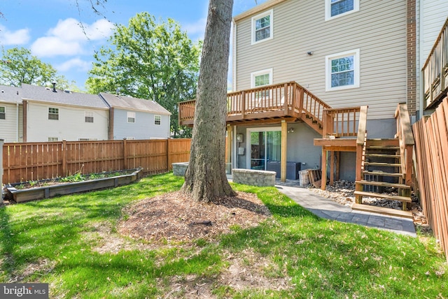 back of property featuring fence, stairs, a deck, a garden, and a lawn