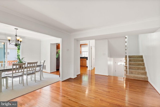 dining room with light wood-type flooring, stairway, baseboards, a notable chandelier, and ornamental molding