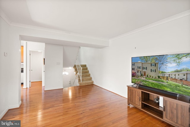 unfurnished living room featuring baseboards, ornamental molding, stairs, and light wood-style flooring