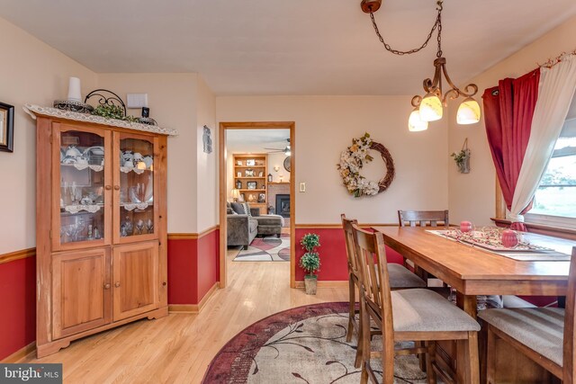 1085 Greenwood Rd, Winchester, VA 22602 - dining room featuring light wood finished floors, a glass covered fireplace, a chandelier, baseboards, and a ceiling fan