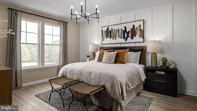 bedroom with baseboards, light wood-type flooring, and an inviting chandelier