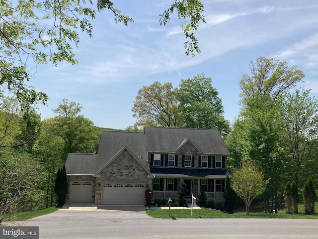 colonial inspired home with concrete driveway, a porch, an attached garage, and stone siding