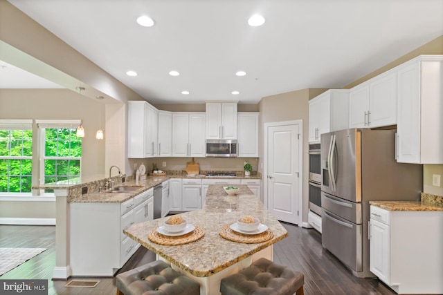 6725 Accipiter Dr, New Market, MD 21774 - kitchen with a sink, a peninsula, stainless steel appliances, a breakfast bar area, and white cabinetry