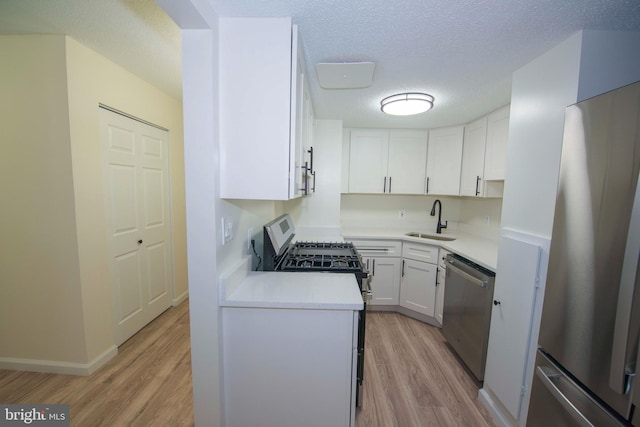 kitchen featuring a sink, white cabinetry, stainless steel appliances, and light wood-type flooring