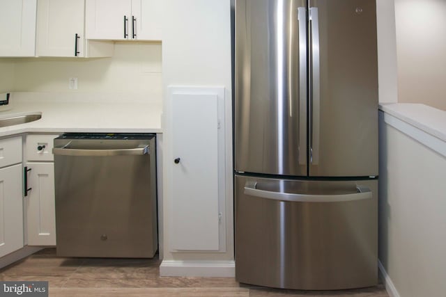 kitchen featuring appliances with stainless steel finishes, light wood-type flooring, light countertops, and white cabinets