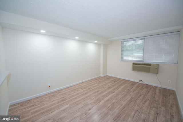 unfurnished room featuring baseboards, a wall mounted air conditioner, wood finished floors, and recessed lighting