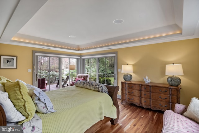 bedroom featuring access to outside, wood finished floors, and a tray ceiling