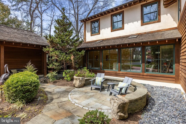 rear view of property with a garage, a patio area, and stucco siding