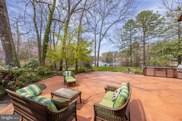 view of patio with a water view, an outdoor hangout area, and an outdoor kitchen