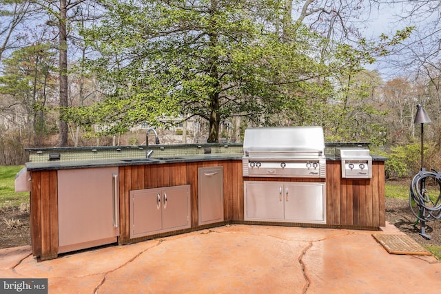 view of patio with an outdoor kitchen, a sink, and area for grilling