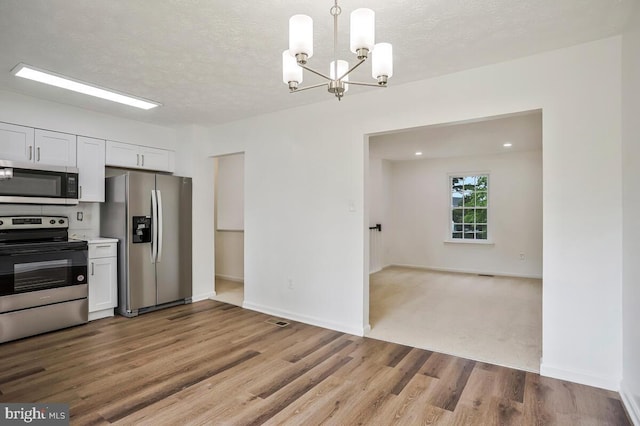1603 Norwich Dr, Frederick, MD 21701 - kitchen featuring appliances with stainless steel finishes, a chandelier, wood finished floors, white cabinetry, and baseboards