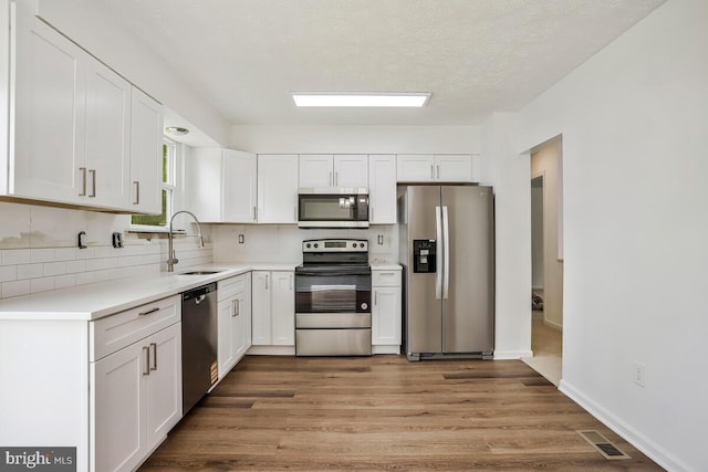 1603 Norwich Dr, Frederick, MD 21701 - kitchen with appliances with stainless steel finishes, a sink, backsplash, white cabinetry, and a textured ceiling