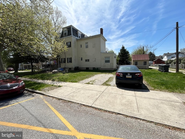 view of side of property with a lawn and uncovered parking